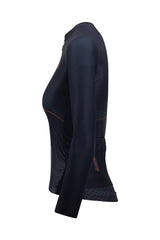 An action shot of a female cyclist wearing a ladies' cycling jersey with long sleeves. The jersey is designed for women riders and offers full arm protection. Its extended sleeves provide additional warmth and coverage, making it suitable for colder conditions. The women's biking jersey has a stylish design and is ideal for cooler weather rides.